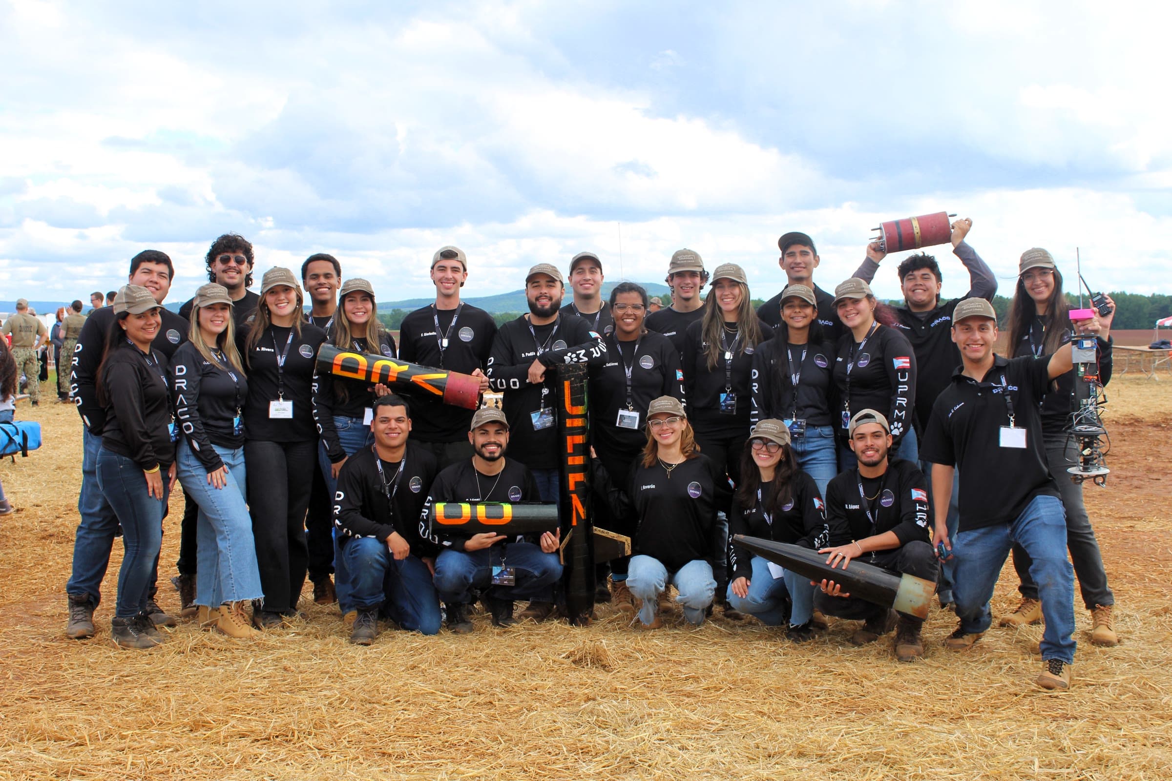 The full DRACO Rocketry Team posing together with rocket components at a launch field