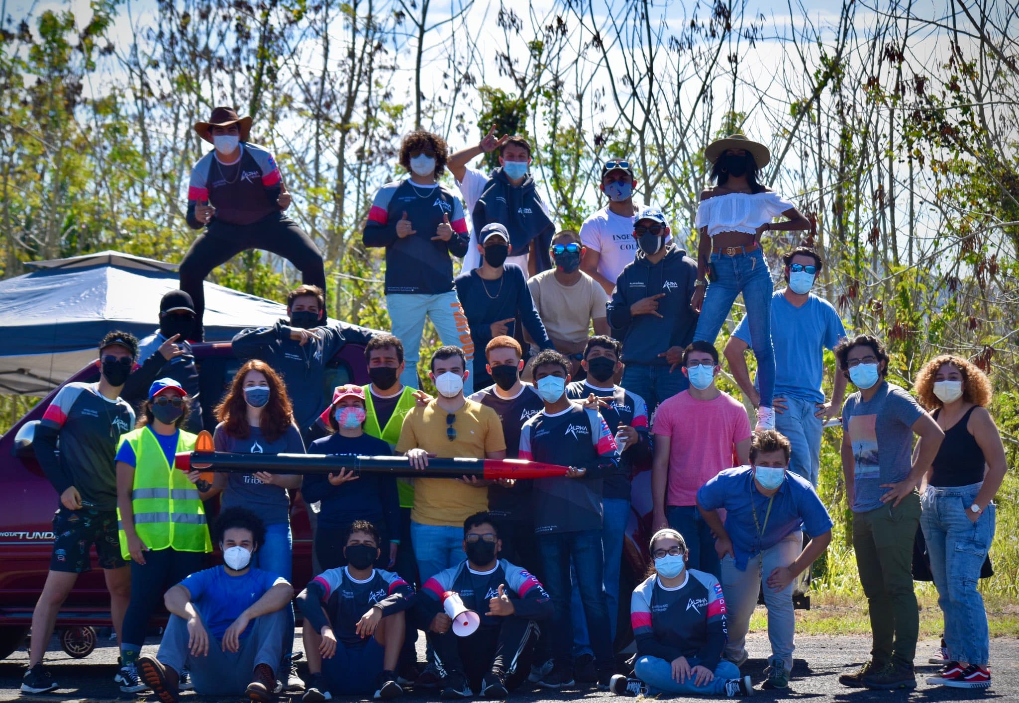 The DRACO team gathered outdoors in masks around the rocket during a test launch campaign